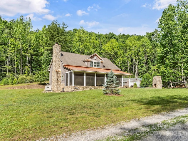 4290 Black Bear Trl, Morganton, NC 28655 - view of front facade with a sunroom, a front lawn, a wooded view, a chimney, and metal roof