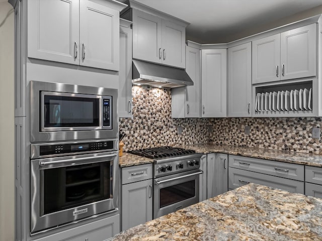 4290 Black Bear Trl, Morganton, NC 28655 - kitchen with appliances with stainless steel finishes, under cabinet range hood, tasteful backsplash, light stone countertops, and gray cabinetry
