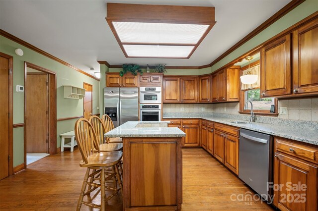 312 Briarwood Dr, Rutherfordton, NC 28139 - kitchen featuring stainless steel appliances, a sink, brown cabinetry, light wood-style floors, and a kitchen island