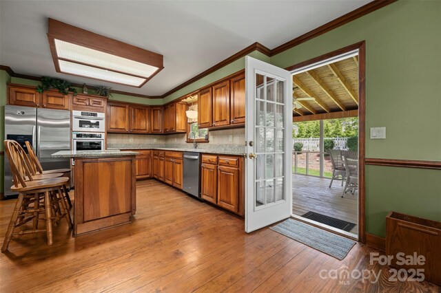 312 Briarwood Dr, Rutherfordton, NC 28139 - kitchen featuring stainless steel appliances, brown cabinets, healthy amount of natural light, backsplash, and ornamental molding