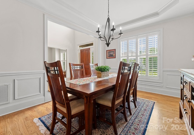 2606 Walker Rd, Matthews, NC 28105 - dining room featuring crown molding, a chandelier, a wainscoted wall, light wood-style floors, and a decorative wall