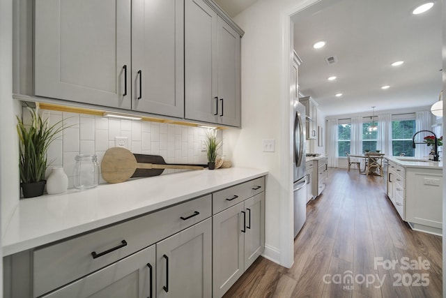 13222 Fiore Pl, Huntersville, NC 28078 - kitchen featuring a sink, gray cabinetry, dark wood finished floors, decorative backsplash, and recessed lighting