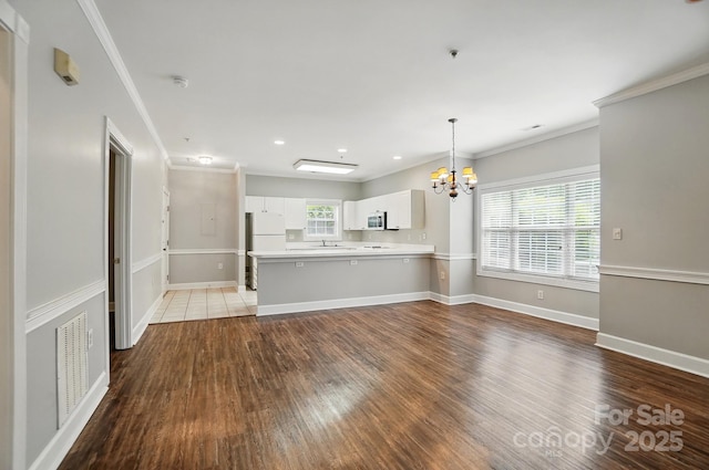 8731 Coralbell Ln, Charlotte, NC 28213 - unfurnished living room featuring a chandelier, wood finished floors, a sink, crown molding, and baseboards