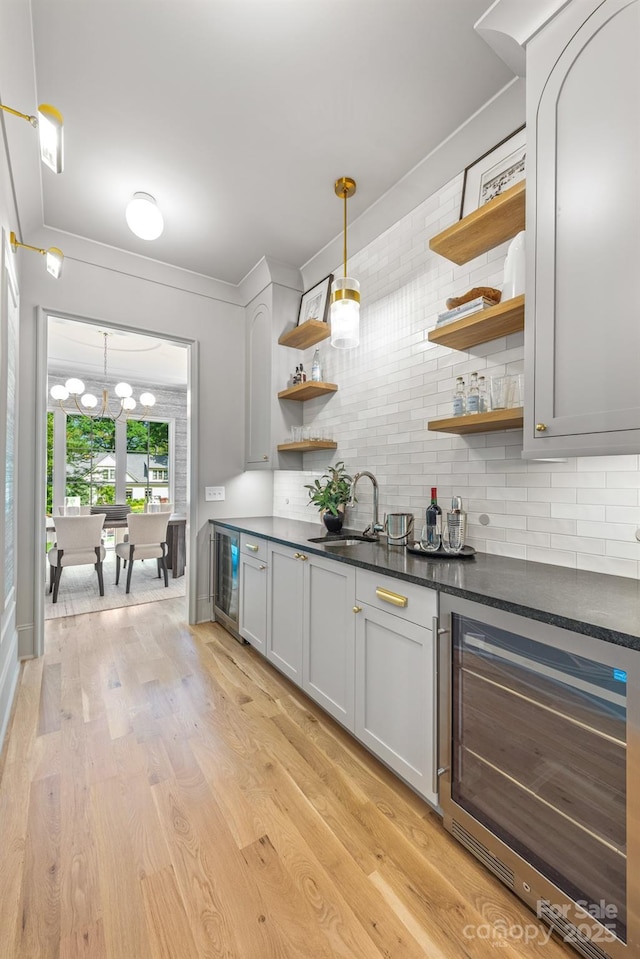 indoor dry bar with beverage cooler, decorative backsplash, and light wood-style floors