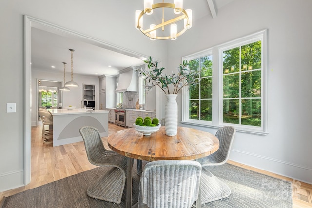 dining room featuring a chandelier, light wood-style flooring, baseboards, and beamed ceiling