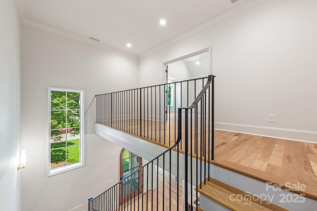 staircase with wood finished floors, ornamental molding, baseboards, and recessed lighting