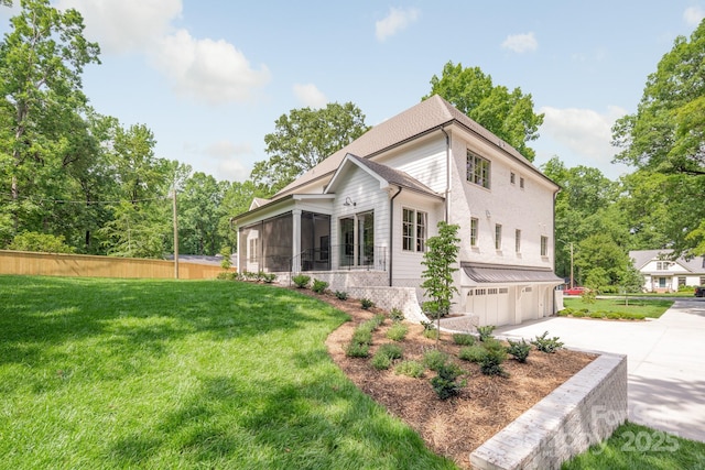 view of home's exterior with an attached garage, a sunroom, and driveway
