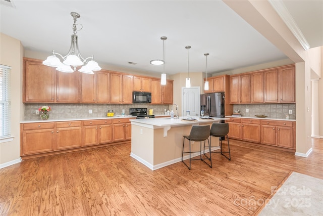 14104 Kendrick Cross Rd, Charlotte, NC 28273 - kitchen featuring black appliances, light wood finished floors, decorative backsplash, a sink, and a kitchen breakfast bar