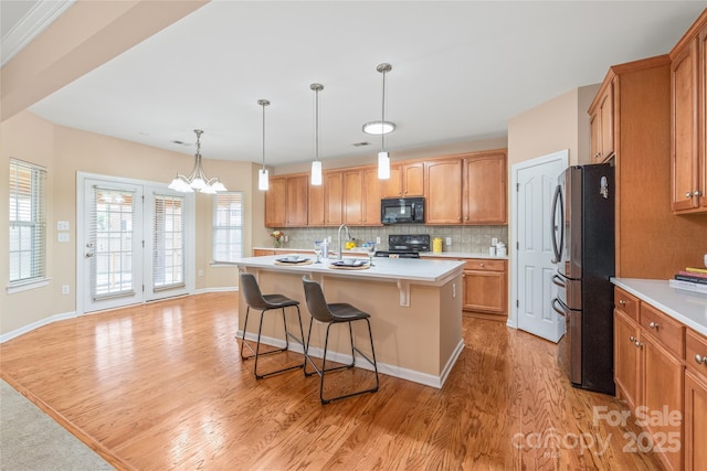 14104 Kendrick Cross Rd, Charlotte, NC 28273 - kitchen with black appliances, light wood-type flooring, a kitchen bar, light countertops, and decorative backsplash