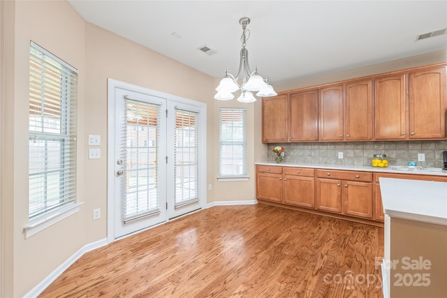 14104 Kendrick Cross Rd, Charlotte, NC 28273 - kitchen with a chandelier, light wood-style flooring, light countertops, hanging light fixtures, and brown cabinets