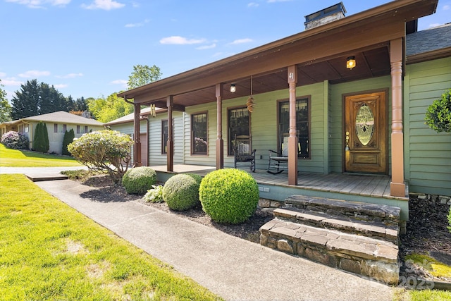 property entrance featuring a porch, a chimney, and a yard