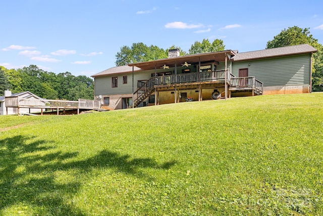 back of property with stairway, a deck, a ceiling fan, a chimney, and a lawn