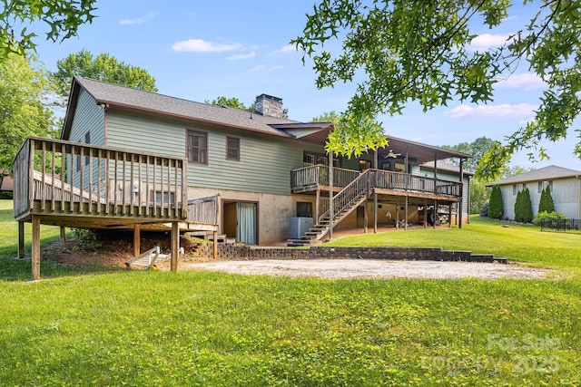 rear view of house featuring stairs, a deck, a chimney, and a yard