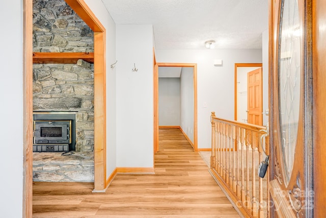 hall with wood finished floors, baseboards, and a textured ceiling