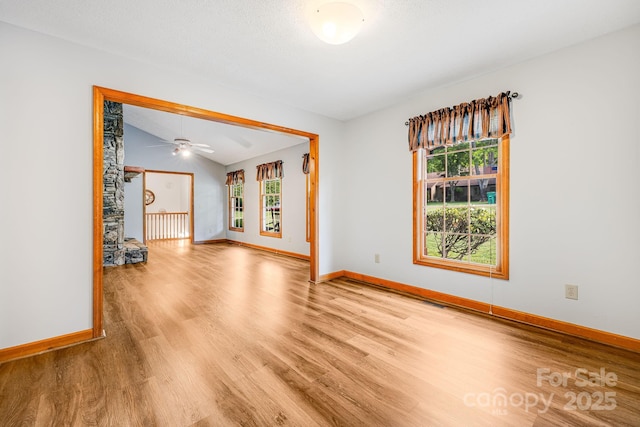unfurnished room featuring wood finished floors, baseboards, lofted ceiling, and a ceiling fan