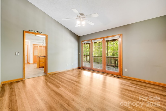 unfurnished room with light wood-style floors, a ceiling fan, high vaulted ceiling, and baseboards