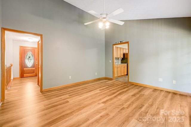 unfurnished room featuring a high ceiling, light wood-style floors, baseboards, and a ceiling fan