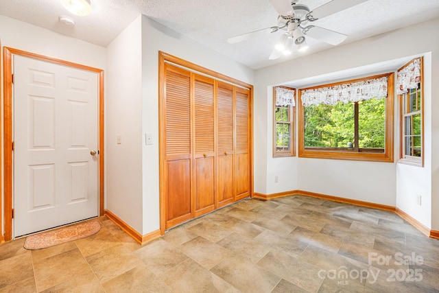 unfurnished bedroom with baseboards, stone finish floors, a closet, and a ceiling fan