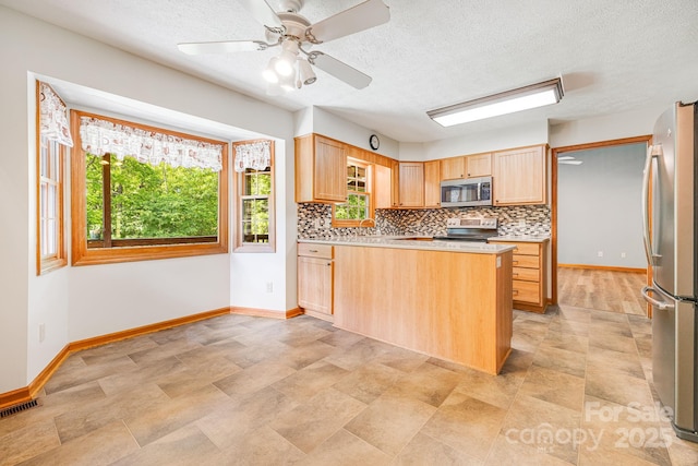 kitchen with appliances with stainless steel finishes, light brown cabinets, baseboards, decorative backsplash, and light countertops