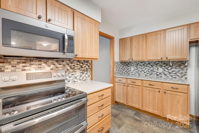 kitchen with appliances with stainless steel finishes, light brown cabinetry, light countertops, and tasteful backsplash