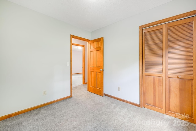 unfurnished bedroom featuring carpet floors, baseboards, a closet, and a textured ceiling