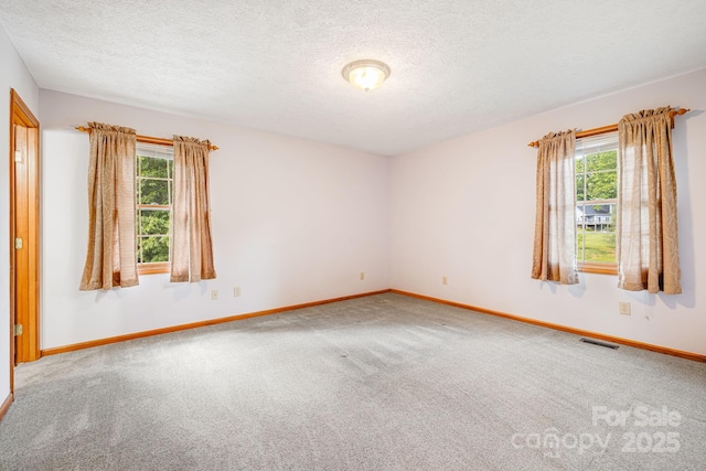 carpeted spare room featuring baseboards and a textured ceiling