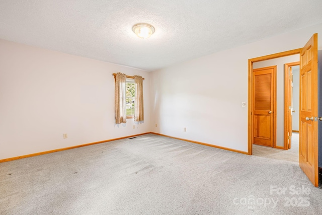 empty room featuring carpet floors, a textured ceiling, and baseboards
