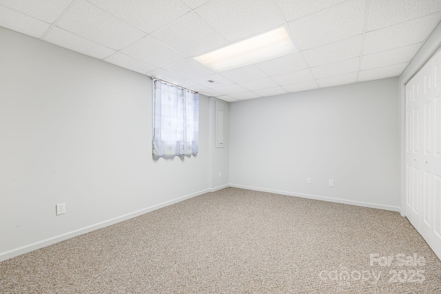 basement with carpet, a paneled ceiling, and baseboards