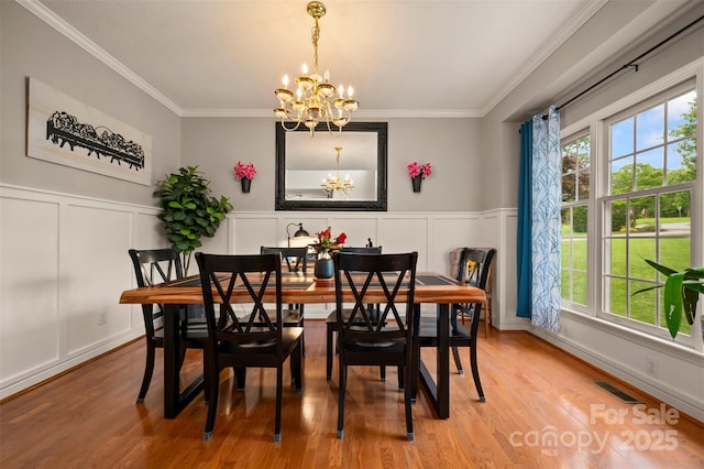 144 Chickasaw Dr, Shelby, NC 28152 - dining space with a chandelier, a decorative wall, ornamental molding, light wood-style flooring, and wainscoting
