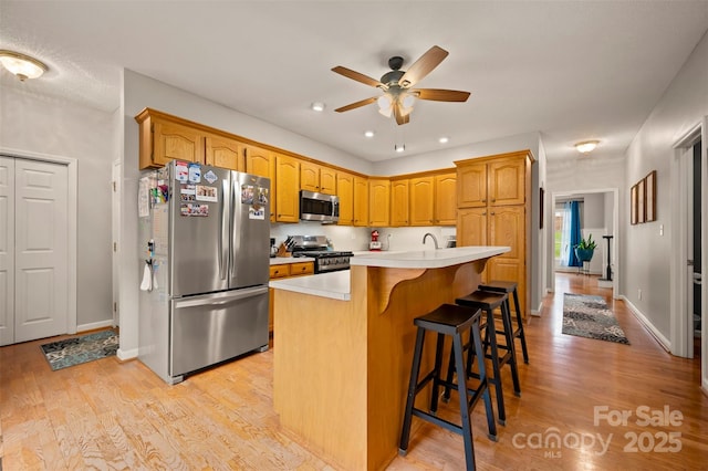 144 Chickasaw Dr, Shelby, NC 28152 - kitchen featuring stainless steel appliances, light countertops, a ceiling fan, a kitchen breakfast bar, and light wood-type flooring
