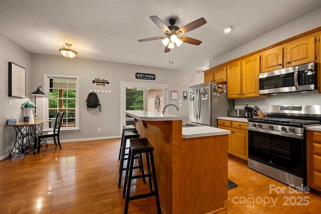 144 Chickasaw Dr, Shelby, NC 28152 - kitchen featuring appliances with stainless steel finishes, a sink, a ceiling fan, a center island with sink, and a kitchen bar