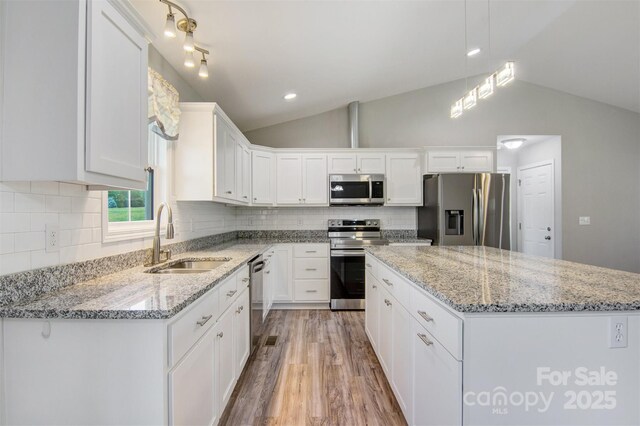 154 Stable Brook Ln, Taylorsville, NC 28681 - kitchen with stainless steel appliances, a sink, vaulted ceiling, a kitchen island, and light wood-style floors