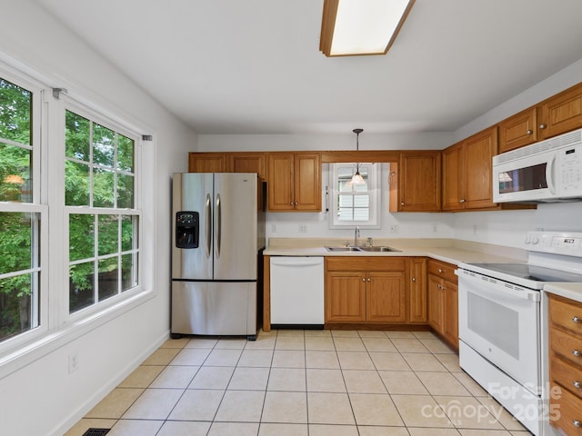 kitchen featuring white appliances, a sink, light tile patterned floors, and light countertops