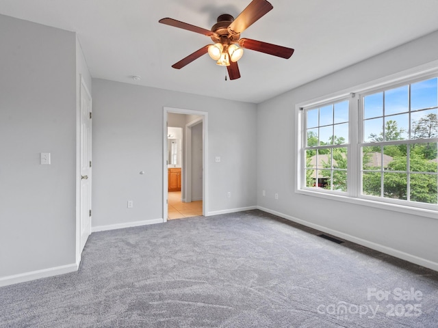 empty room featuring healthy amount of natural light, ceiling fan, light colored carpet, and baseboards