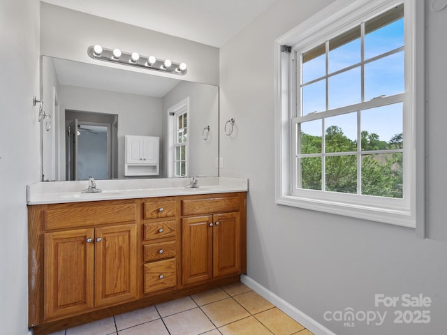 full bathroom featuring healthy amount of natural light, tile patterned floors, double vanity, and baseboards