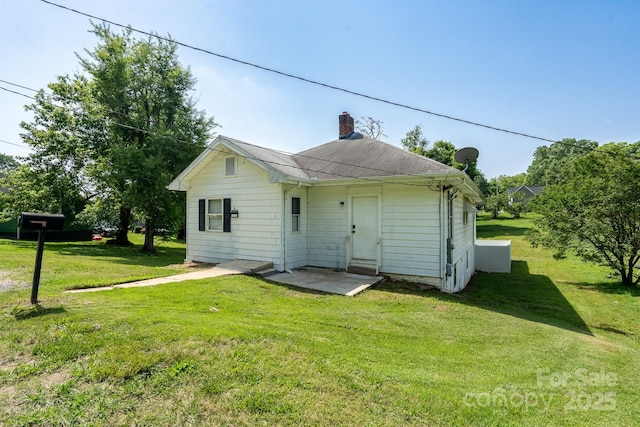 rear view of house with a chimney and a lawn