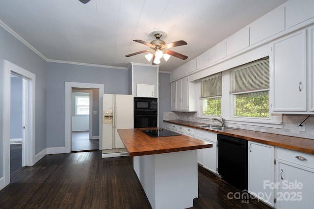 kitchen featuring butcher block counters, a sink, black appliances, tasteful backsplash, and white cabinetry