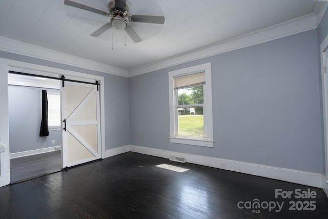 unfurnished room featuring crown molding, a barn door, dark wood-style floors, baseboards, and a ceiling fan