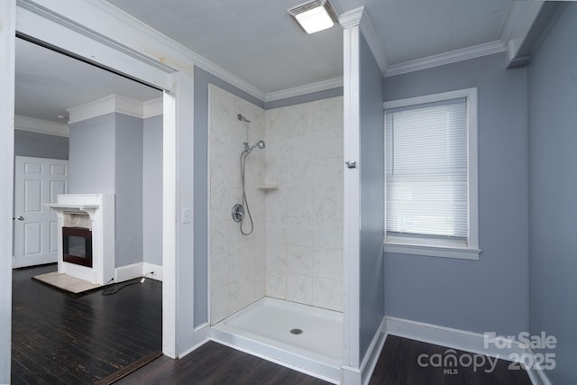 bathroom featuring baseboards, tiled shower, wood finished floors, and crown molding