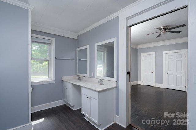 bathroom featuring ornamental molding, wood finished floors, double vanity, ceiling fan, and baseboards