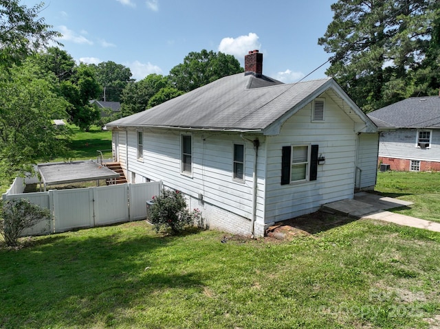 view of side of property with a gate, a chimney, and a shingled roof