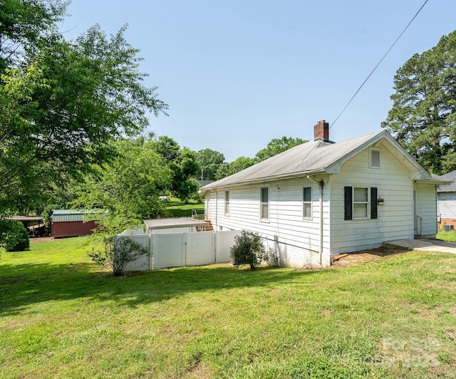 view of side of home with a chimney and a gate
