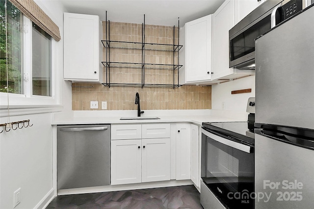 kitchen featuring stainless steel appliances, a sink, light countertops, backsplash, and white cabinetry