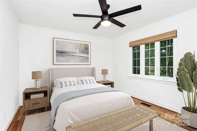 bedroom featuring wood finished floors, baseboards, and a ceiling fan