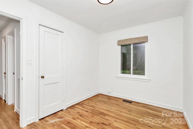 unfurnished room with light wood-type flooring, crown molding, and baseboards