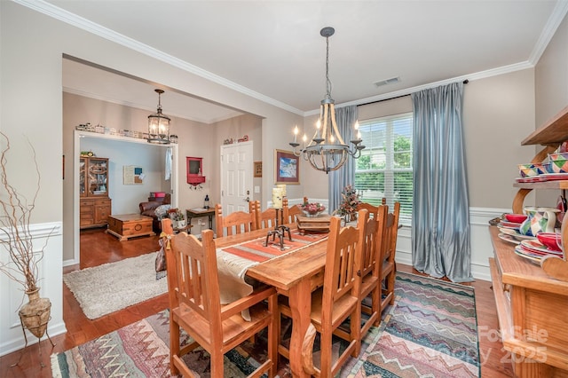 dining room with a chandelier, ornamental molding, and wood finished floors