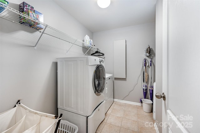 clothes washing area with independent washer and dryer, baseboards, and light tile patterned floors