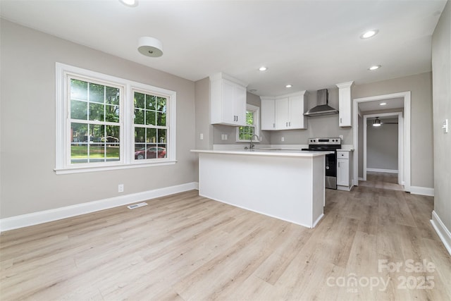 3920 Admiral Ave, Charlotte, NC 28205 - kitchen featuring stainless steel electric range, wall chimney exhaust hood, white cabinetry, light wood-style flooring, and light countertops
