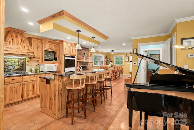 751 Millers Pond Ln, Boone, NC 28607 - kitchen featuring white appliances, custom range hood, a center island with sink, a kitchen breakfast bar, and crown molding