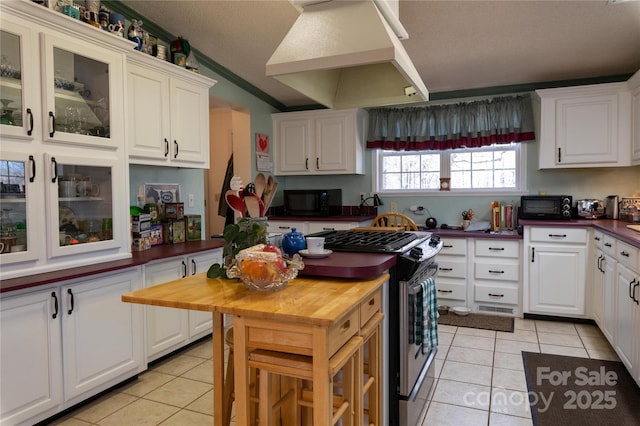 120 Powderhorn Dr, Burnsville, NC 28714 - kitchen with custom exhaust hood, light tile patterned floors, black microwave, stainless steel gas range, and wooden counters